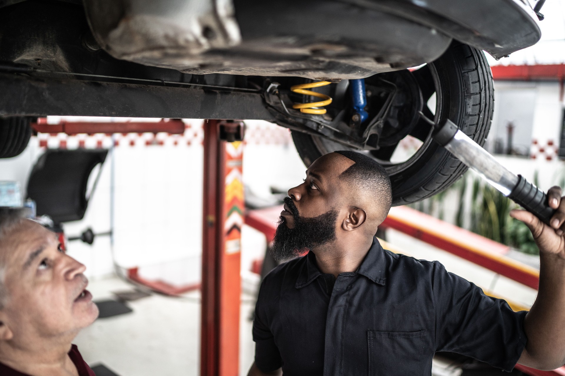 Mechanic man explaining the service to be done to his client in car - under the vehicle